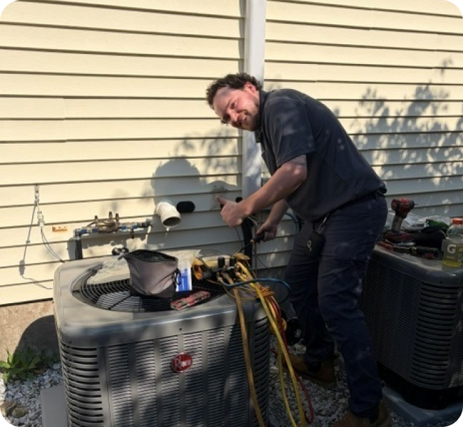 Caron technician repairing a heat pump condenser at a Merrimack Valley home