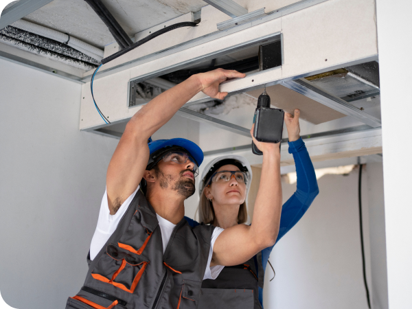 Installers fitting ductwork for a central air conditioning system