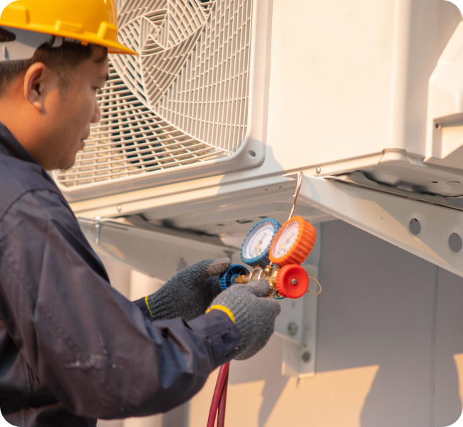 Technician testing refrigerant levels on an AC unit with service gauges