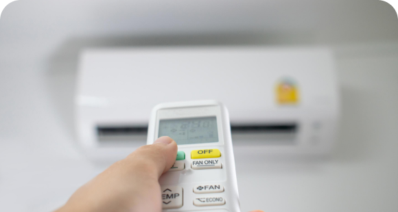 Homeowner adjusting a ductless mini-split with a remote control