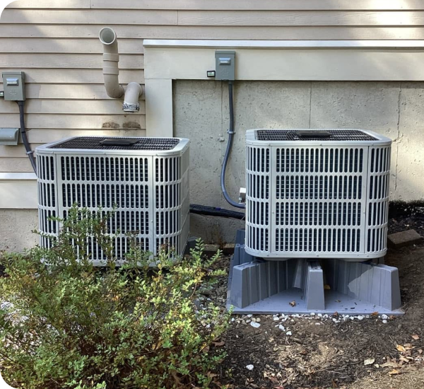 Two central air conditioner condensers installed outside a Haverhill area home