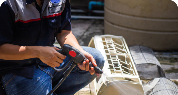 Technician cleaning an AC unit during maintenance