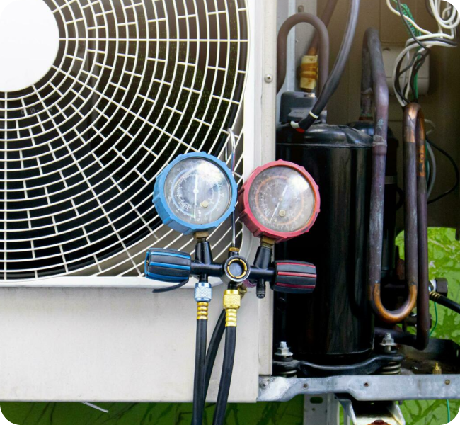 Refrigerant gauges connected to a heat pump compressor during repair