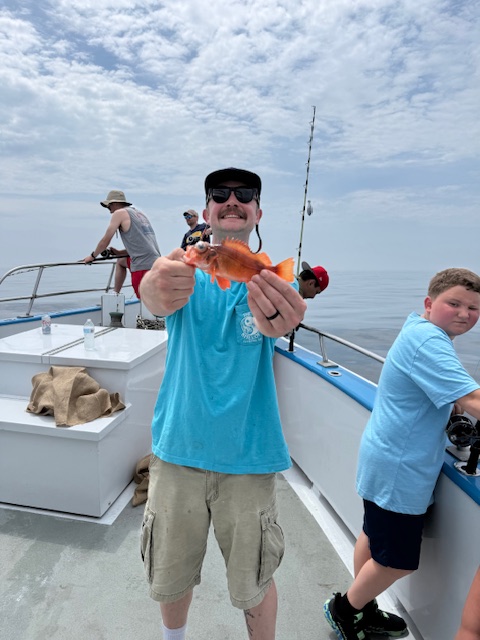 A Caron Heating & Cooling team member holding up his catch during the annual fishing outing