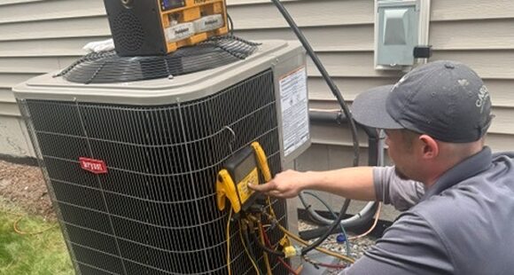 Caron Heating & Cooling technician servicing a Bryant central air conditioner