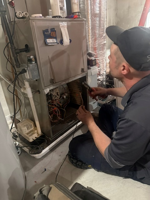 Caron Heating & Cooling technician repairing a furnace control board