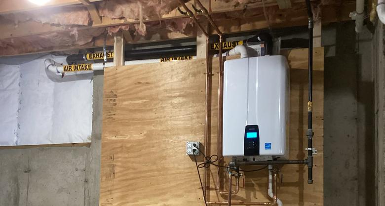 Navien wall-mounted tankless water heater installed by Caron Heating & Cooling in a Merrimack Valley basement